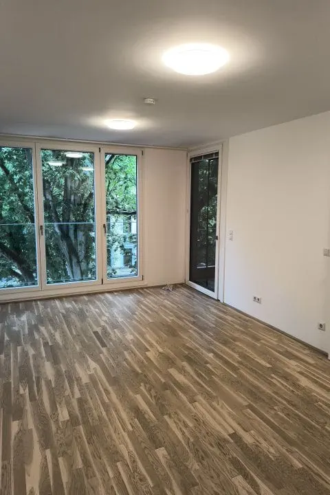 Biber Sanierung – Referenz Wohnungssanierung: heller Wohnraum mit Parkettboden und Balkontüren
