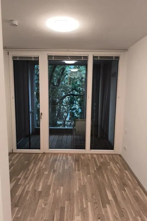 Biber Sanierung – Referenz Wohnungssanierung: Zimmer mit Parkett und Balkonverglasung